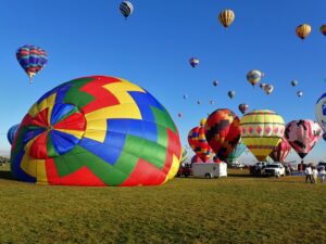 A hot air balloon inflates on the ground in front of several other airborne balloons