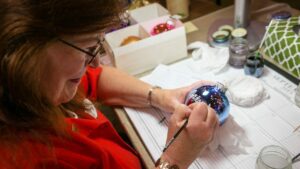 A craftsperson hand decorating an ornament in Frankenmuth