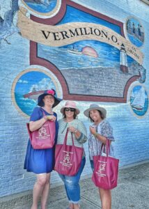 a trio of women standing in front of a mural in Vermillion