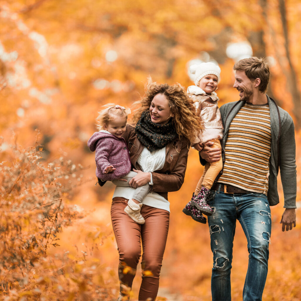 A picture of a family walking through a park filled with vibrant fall colors.