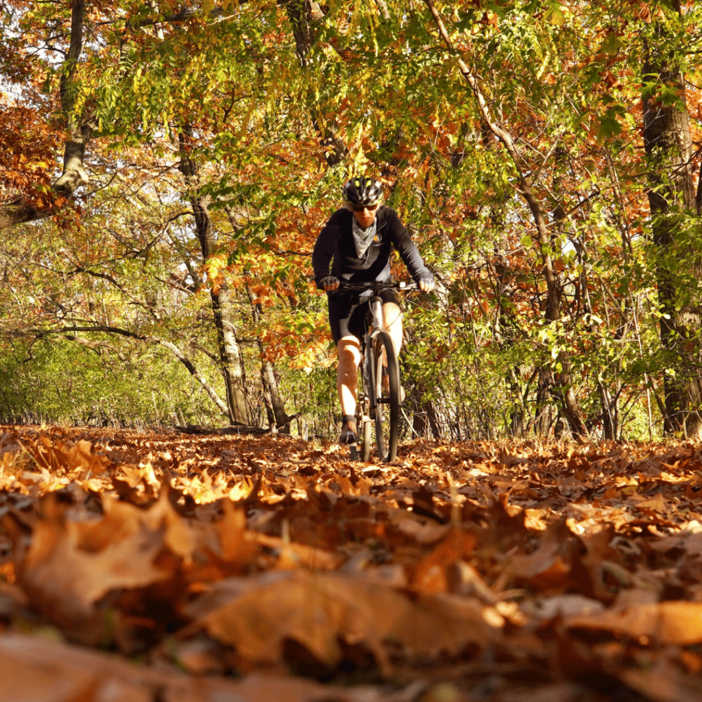 Man enjoying cold weather cycling over bed of fallen leaves