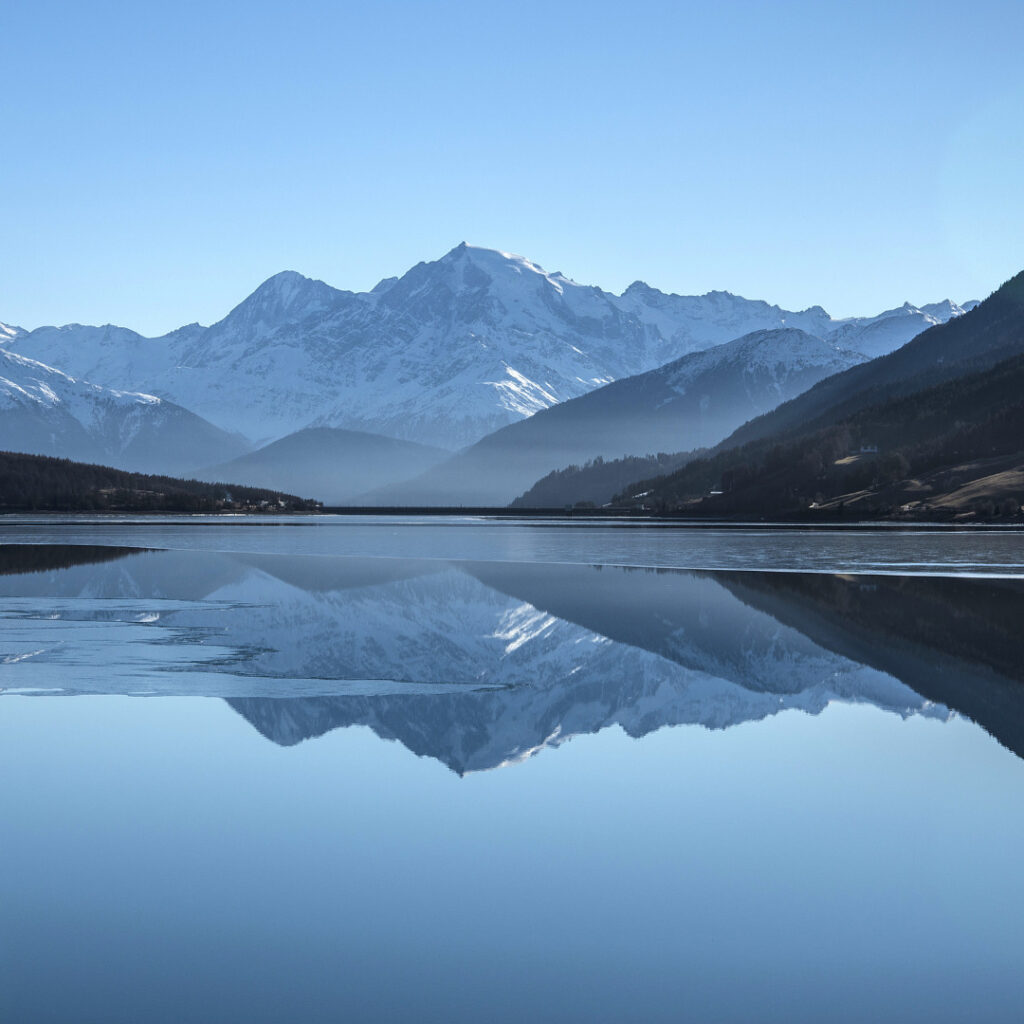 A calm lake reflecting cold rugged mountains in the background.