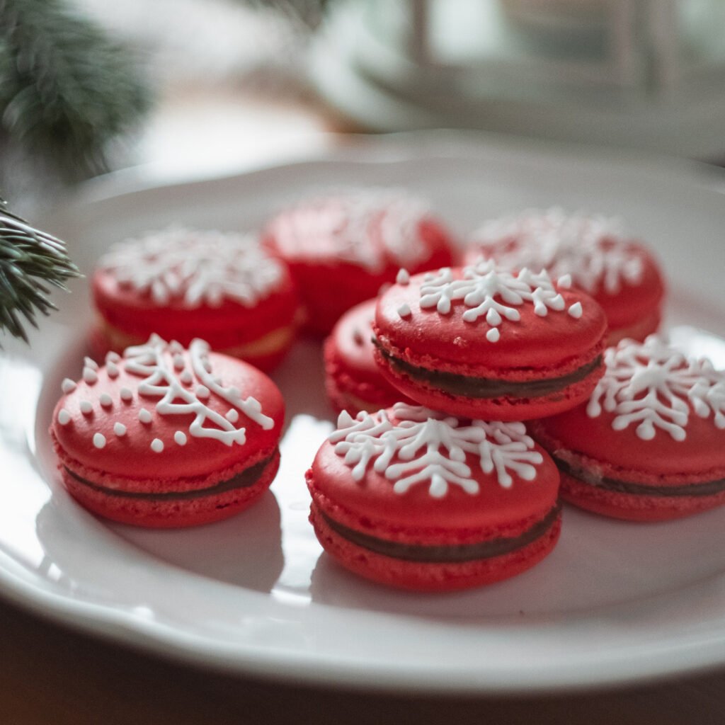 A plate of Christmas cookies; Red Macaroons with iced snowflakes on top