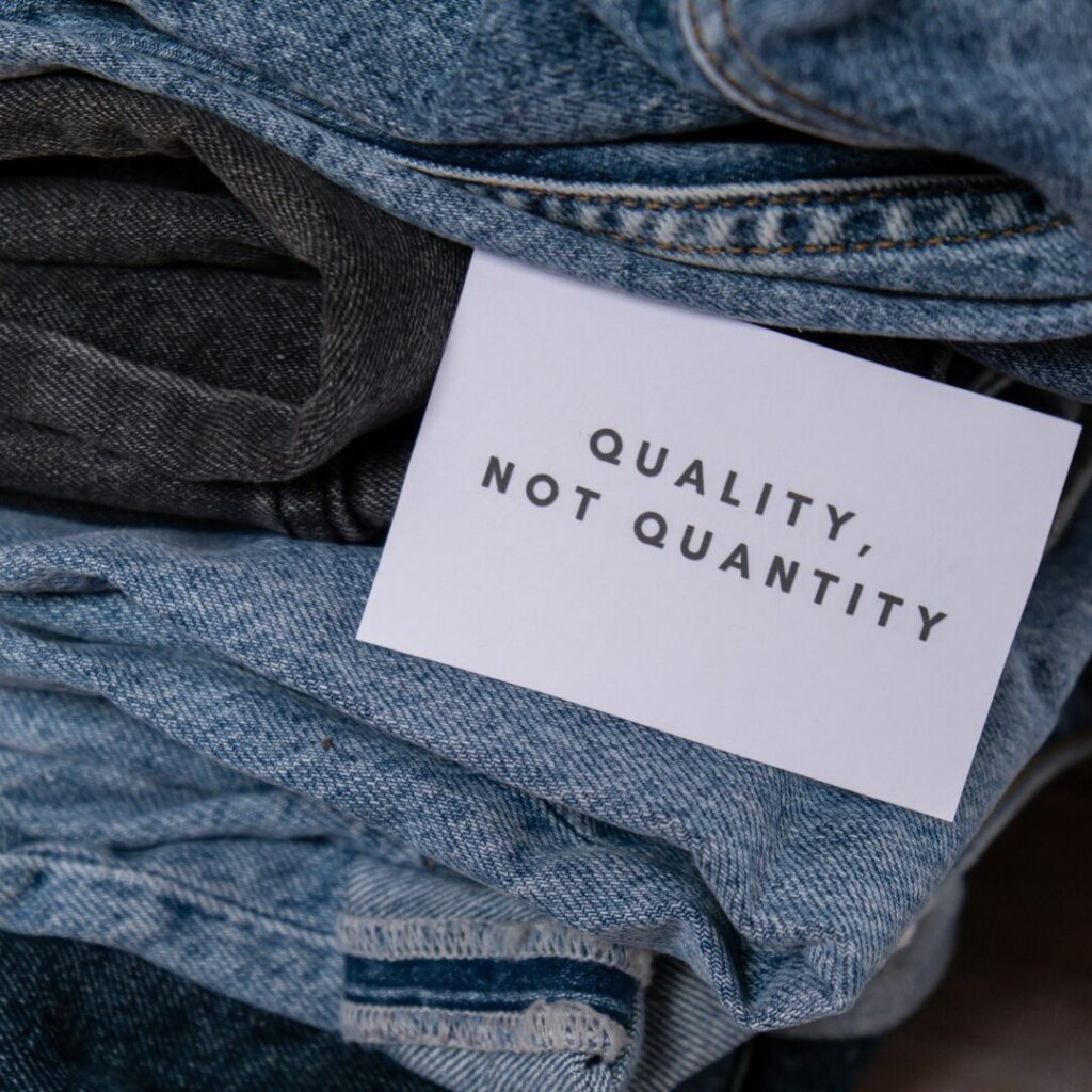 A stak of jeans with a sign saying "Quality over Quantity."