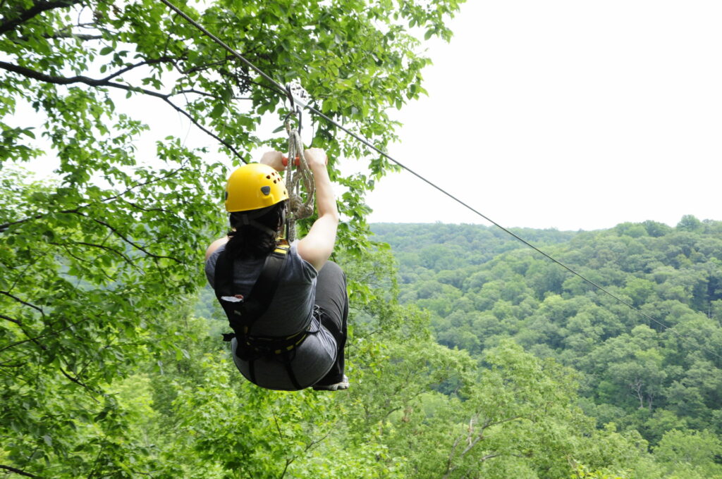 A woman ziplining through the trees in Warren County, knonw as Ohio's Largest Playground