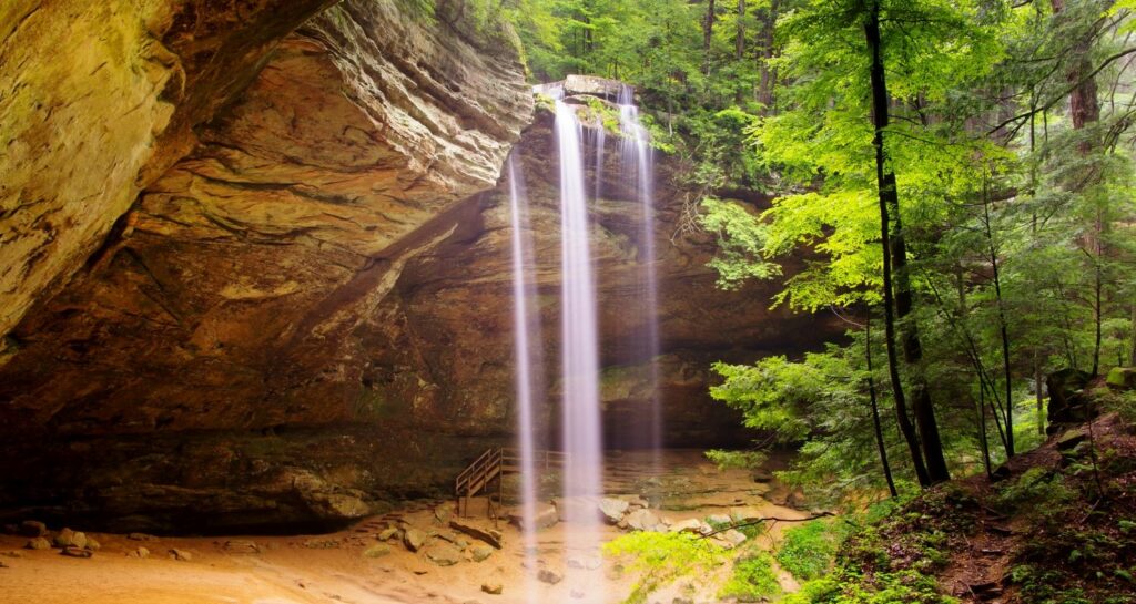 Veils of water streams down the rocky ledge at Ash Cave Waterfall in Hocking Hills Ohio