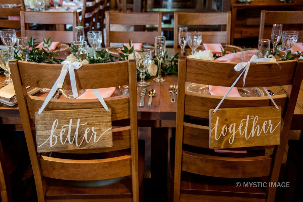 A rustic table with two chairs set for a wedding with a Better sign and a together sing hanging from the back of the chairs at Carroll County Wedding Venues