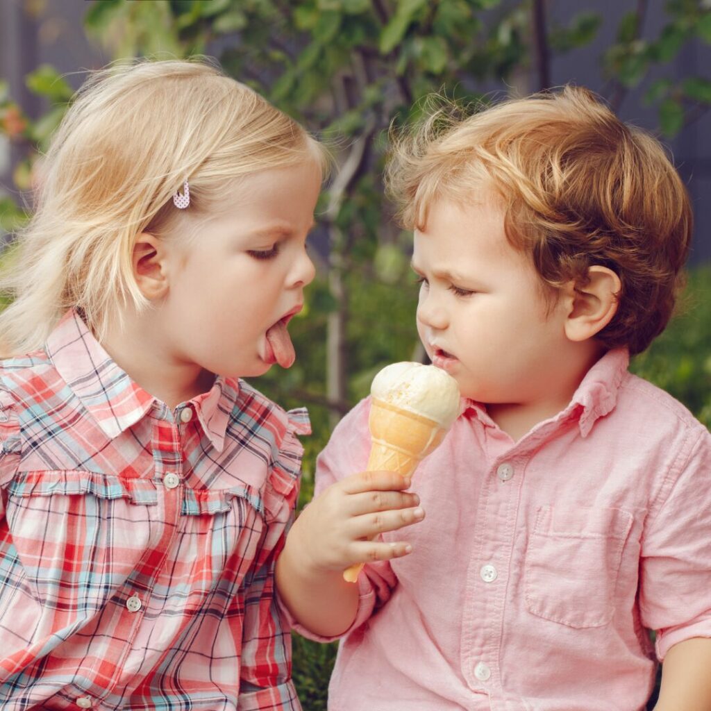 The battle over Ohio Ice Cream. A little girl is leaning in for a lick off a little boy who is holding his ice cream cone and does not want to share with her.