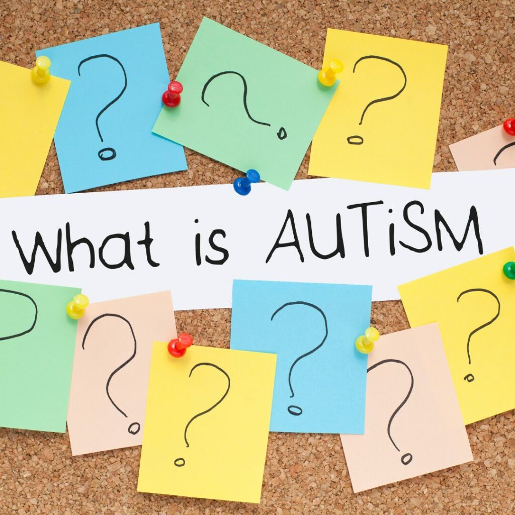 A peg board with a paper saying "What is Autism" surrounded by question marks on post its