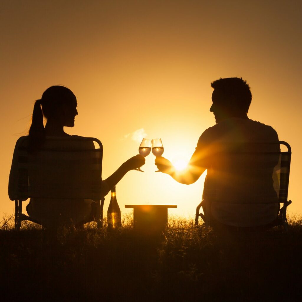 A couple is watching a sunset and enjoying a glass of wine on their low budget date night